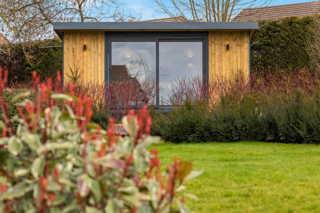 Redwood clad garden studio in background with out of focus bushes in the front.