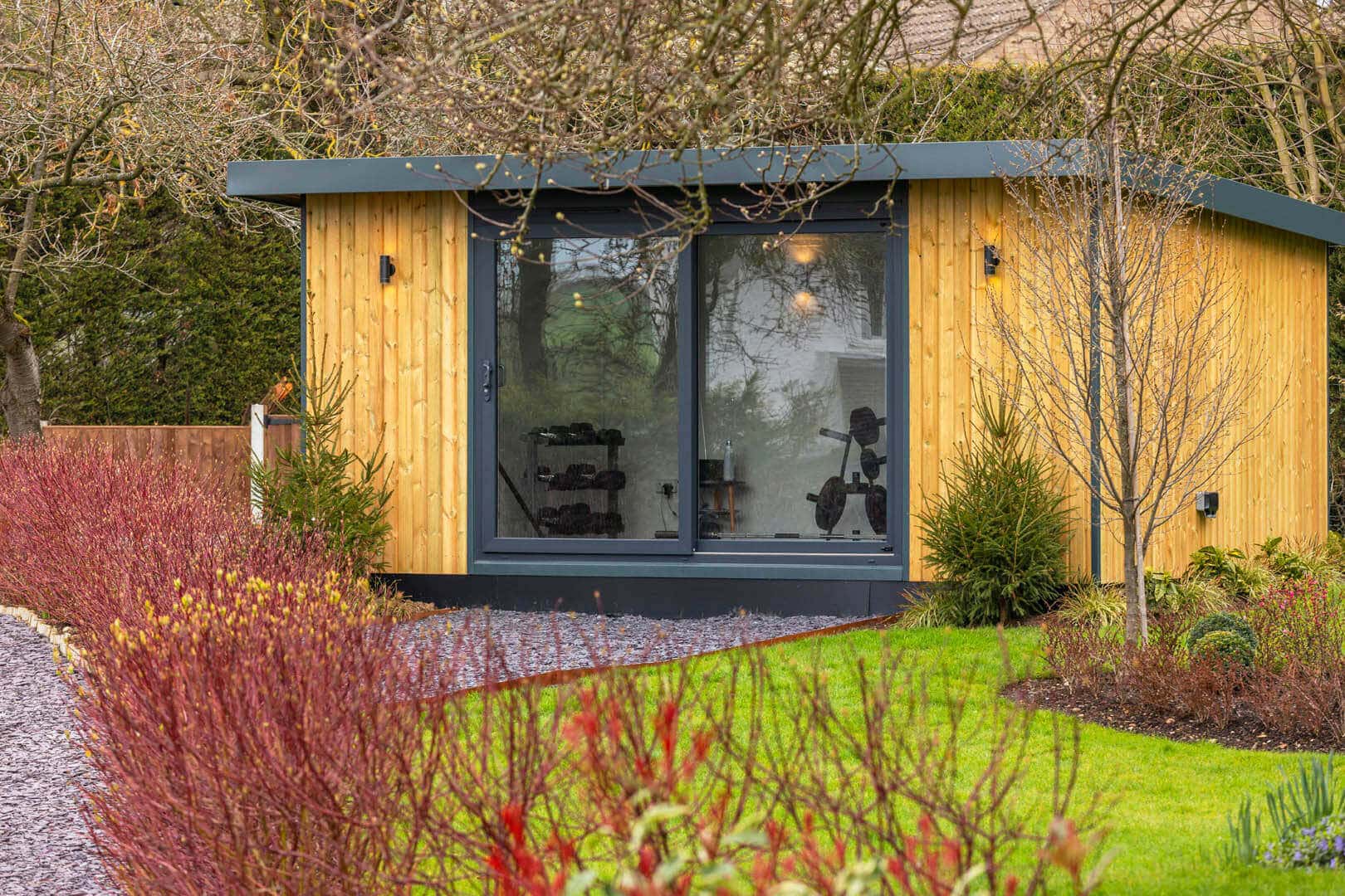 Large garden studio with sliding doors and autumnal shrubs in the foreground.