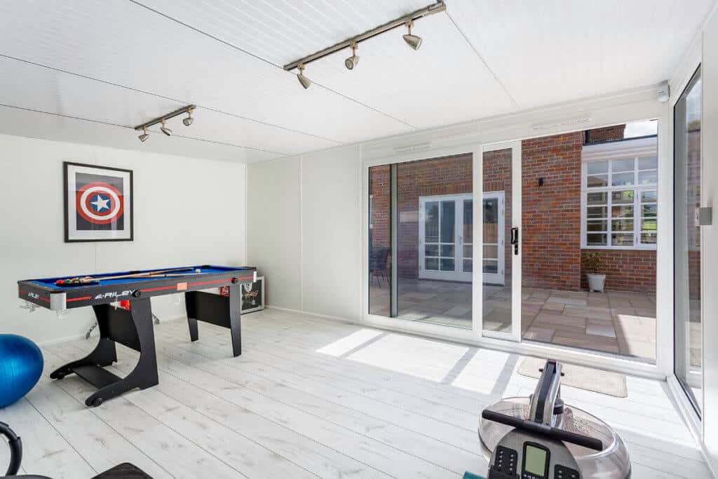 Pool table in garden games room with white walls and white oak laminate flooring