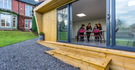 A group of students working around a table in a Green Retreats classroom with sliding doors