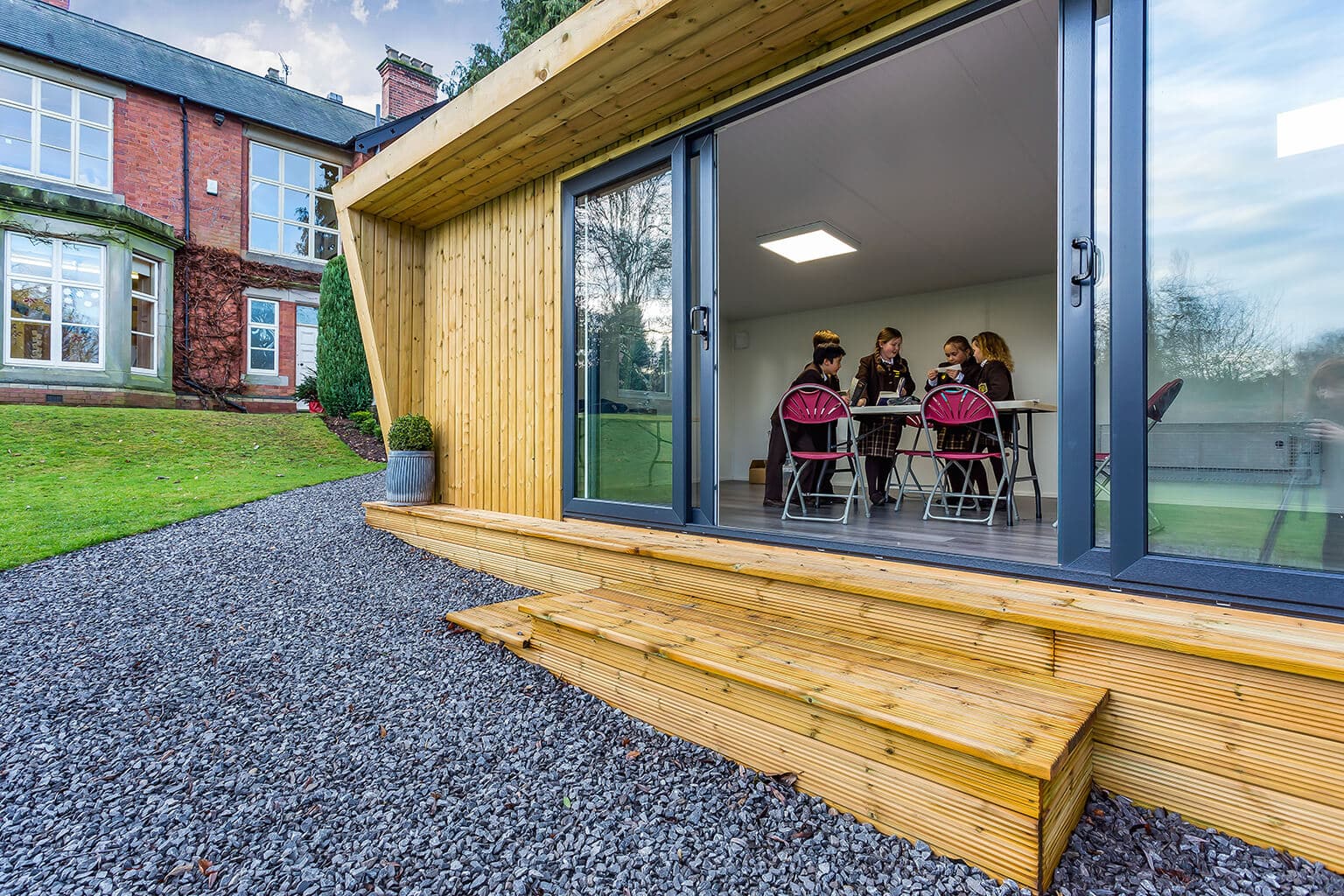 A group of students working around a table in a Green Retreats classroom with sliding doors