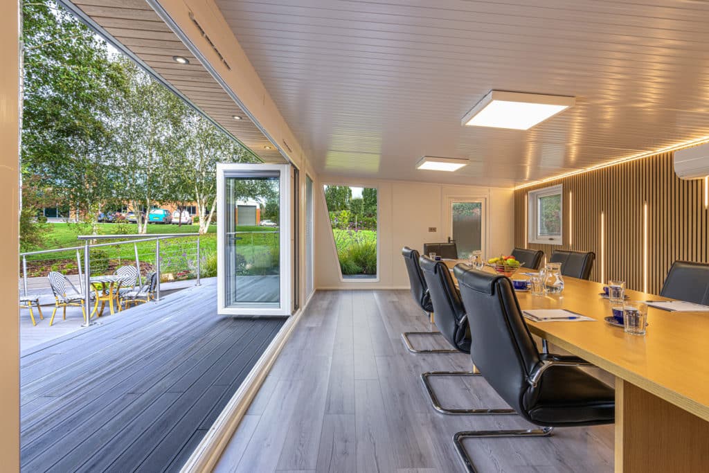 Interior of a boardroom with bi-fold doors open looking out onto a patio and garden