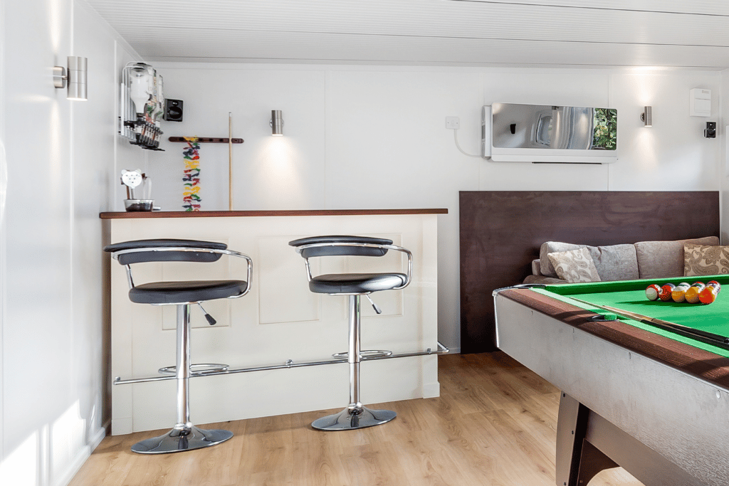 Bar island with stools in the corner of garden room with snooker table in the foreground and optics on the wall 