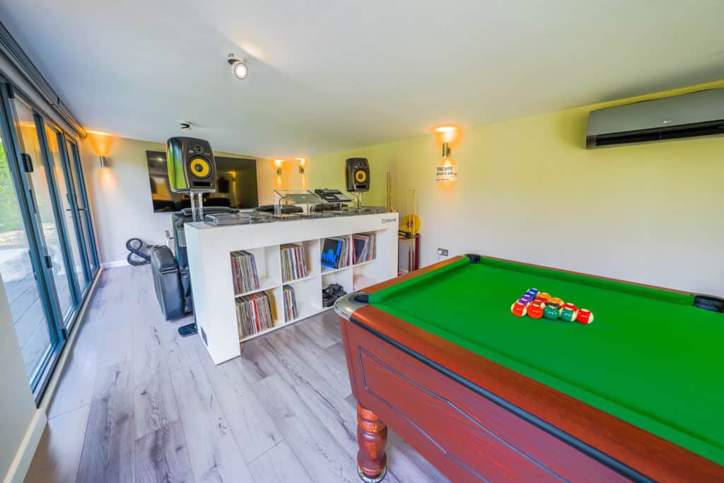 Interior of a man cave with a pool table with pool balls arrange on it and a DJ booth behind it