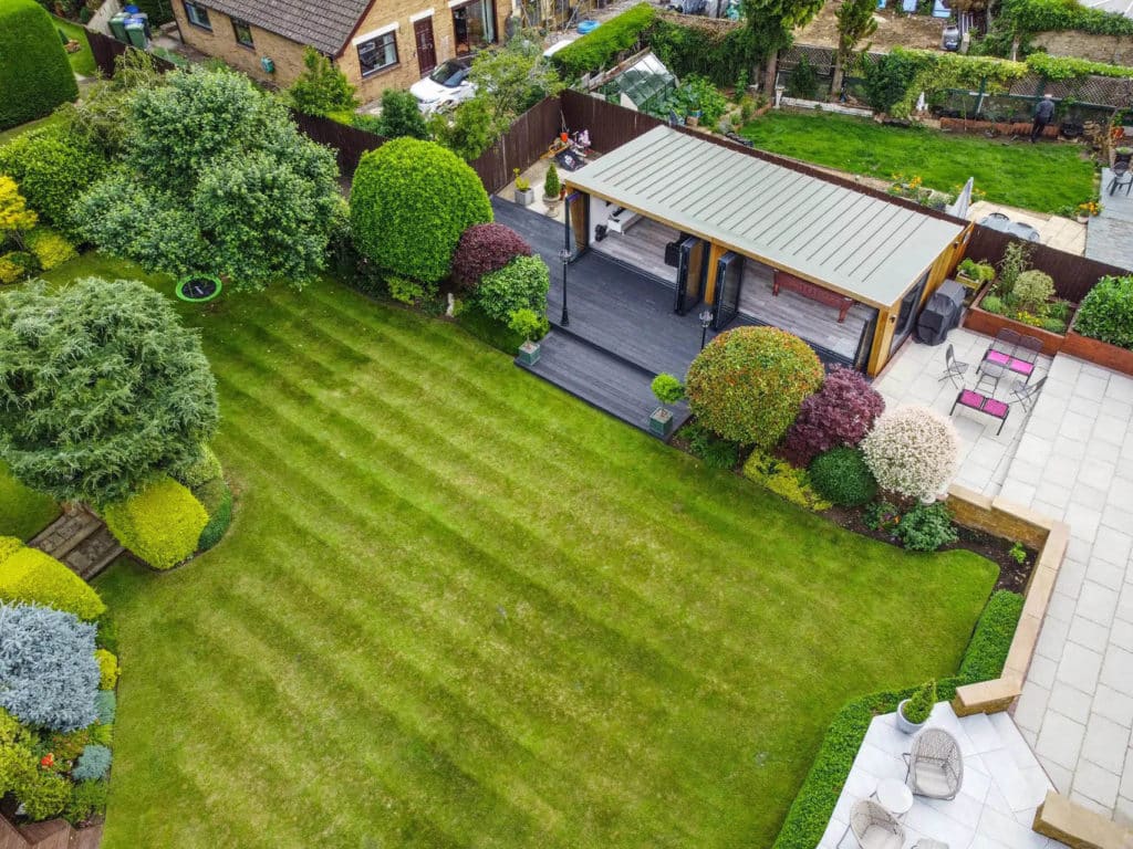 Exterior drone shot of a man cave in a landscaped garden with two large open bi-fold doors