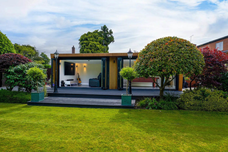 Exterior of a man cave with two bi-fold doors open looking into a home cinema