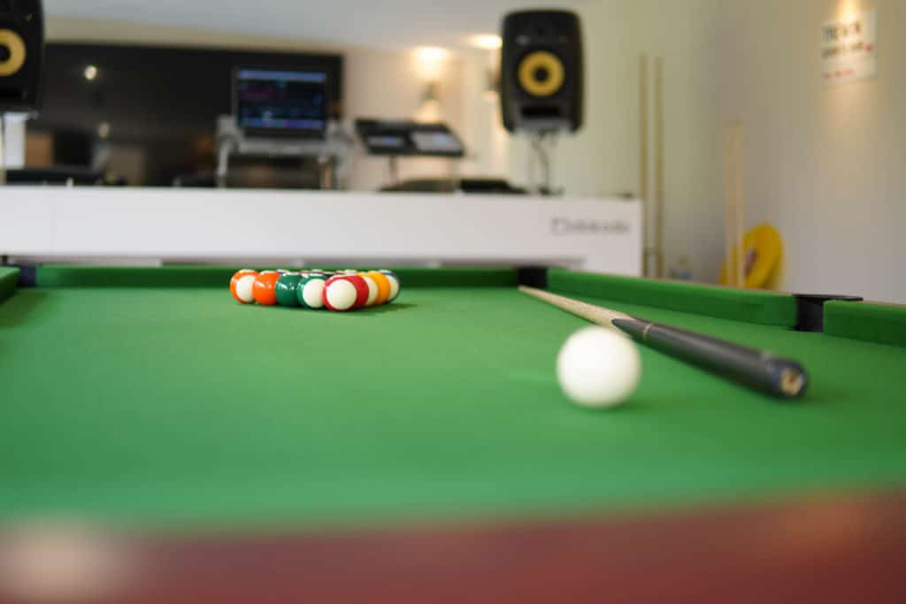 Close up of a low angle pool table with a DJ deck in the backgrounds