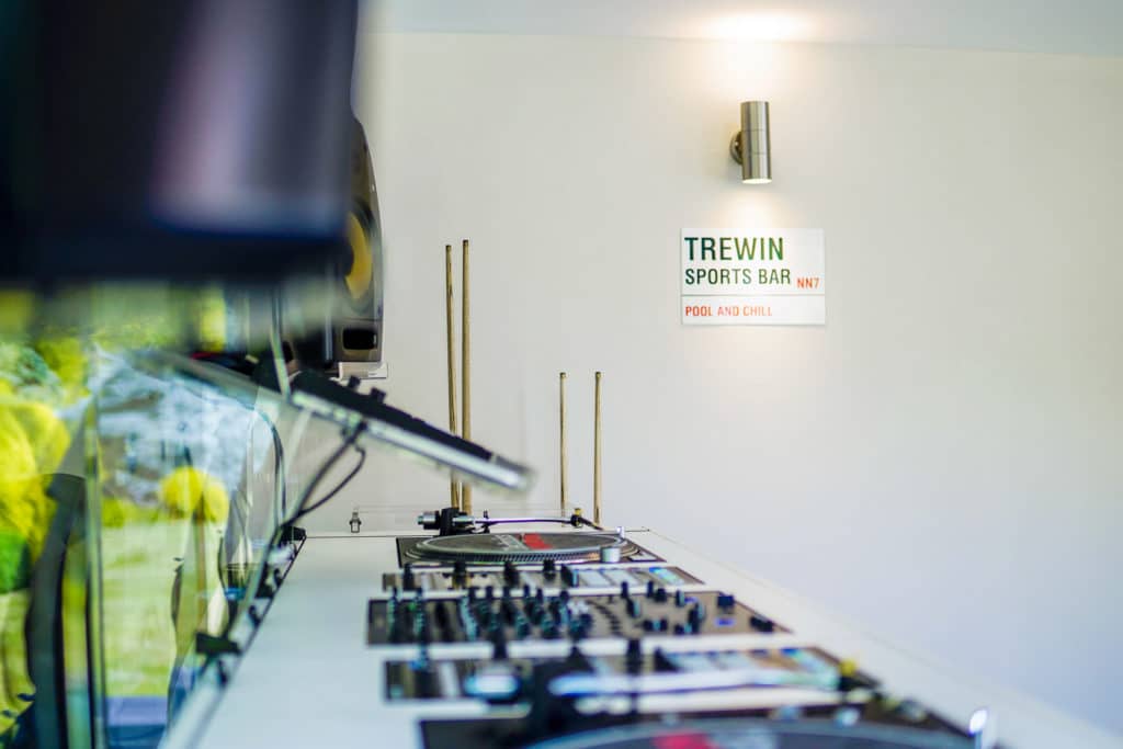 Close up of a DJ decks with a road side reading 'Trewin Sports Bar NN7' on the back wall of a man cave