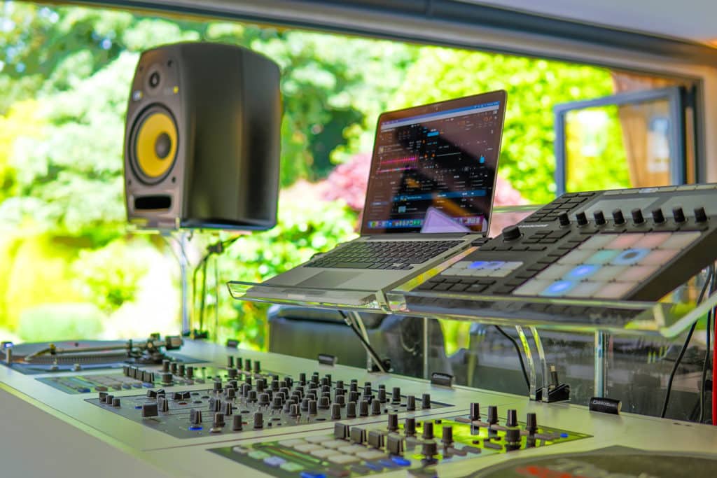 DJ deck with an open laptop and speakers in the distance