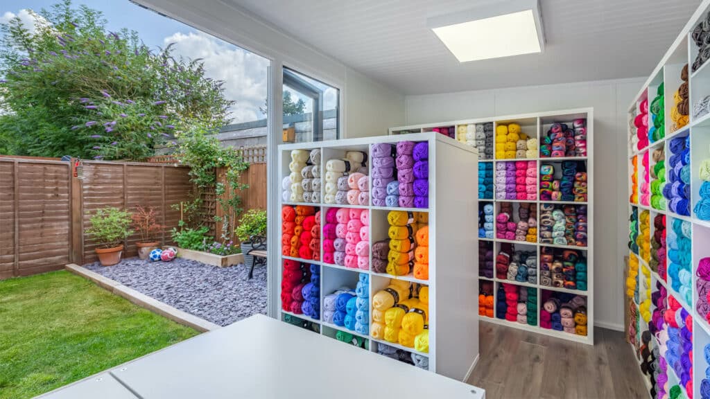 Interior of home office being used as a yarn business with shelves of colourful yarn inside