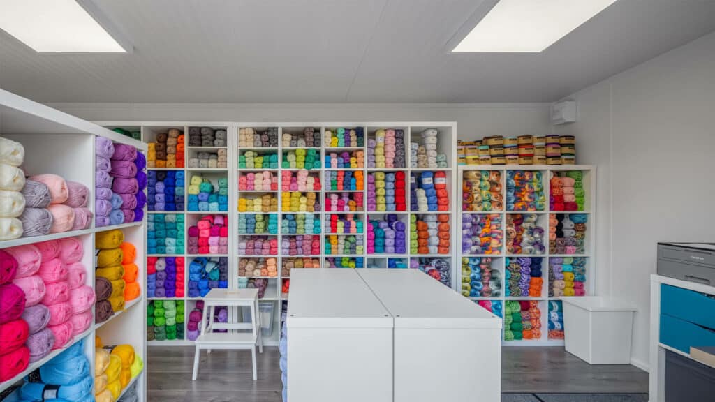 Interior home office being used as a yarn business with shelves of colourful yarn inside