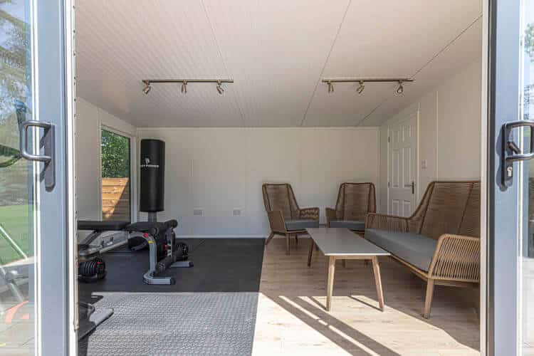 Section of the interior of a garden room with gym equipment and garden lounge set