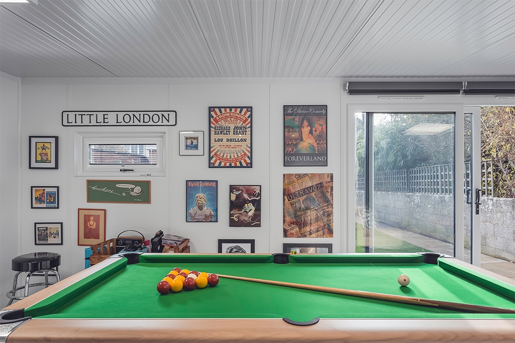 Green Retreats man cave with a pool table & music posters on the wall
