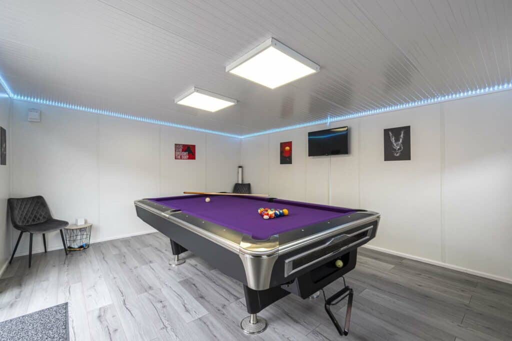 Games room view. LED blue lights in the edge of the ceiling and artwork on the walls