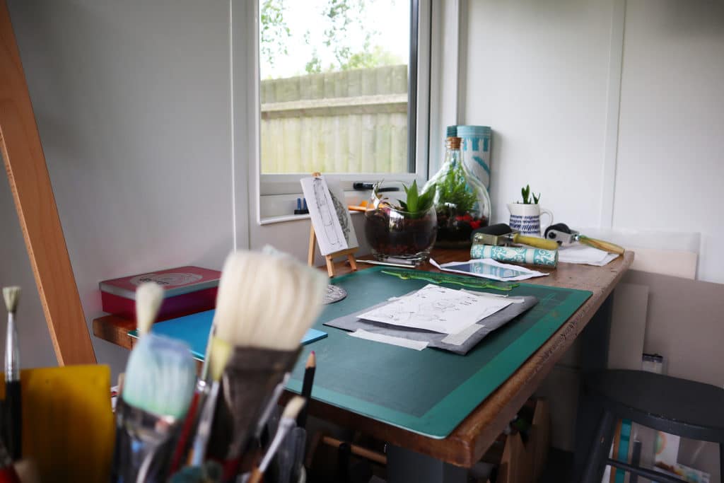 Close up shot of inside garden room art studio showing work desk and brushes