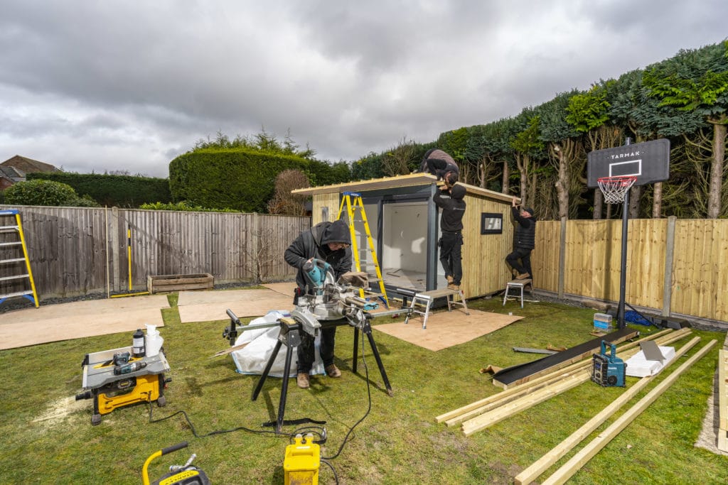 Three installers building the shell of the garden room in customers garden