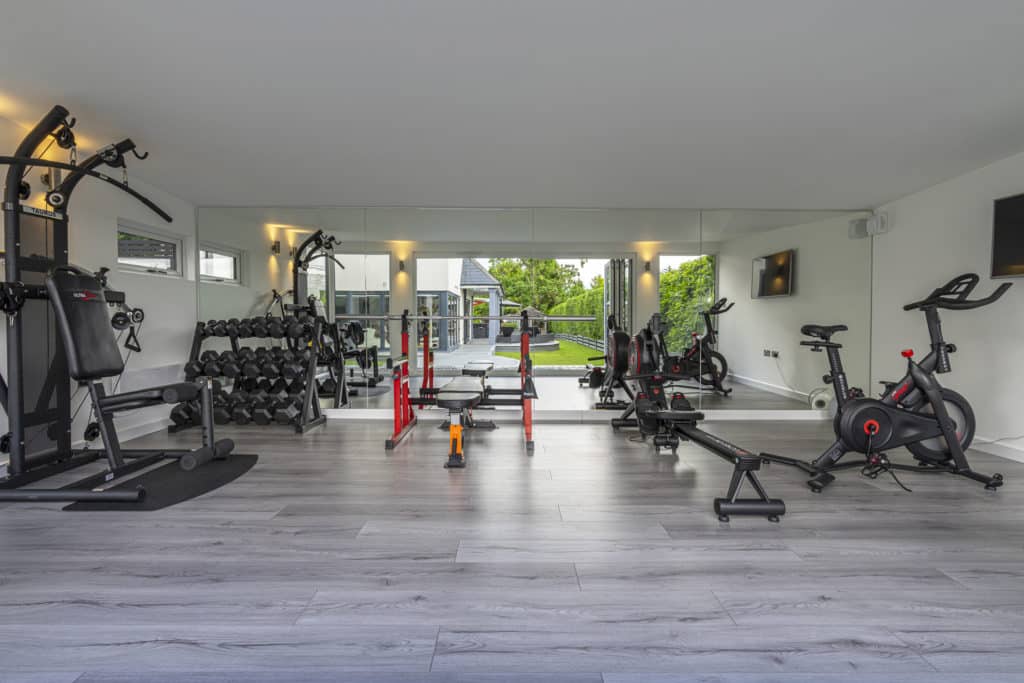 Interior of garden gym with mirrors on the back wall showing reflection into garden