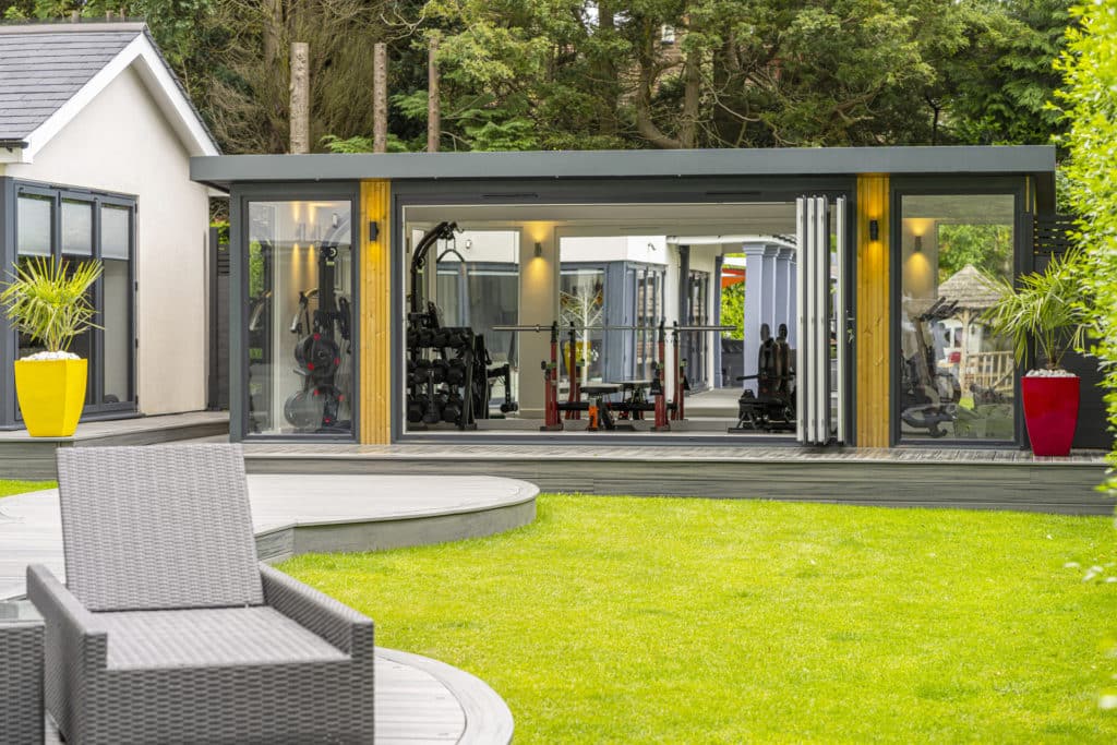Garden room home gym with reflection in mirrored wall showing garden reflection