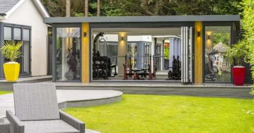 Garden room home gym with reflection in mirrored wall showing garden reflection