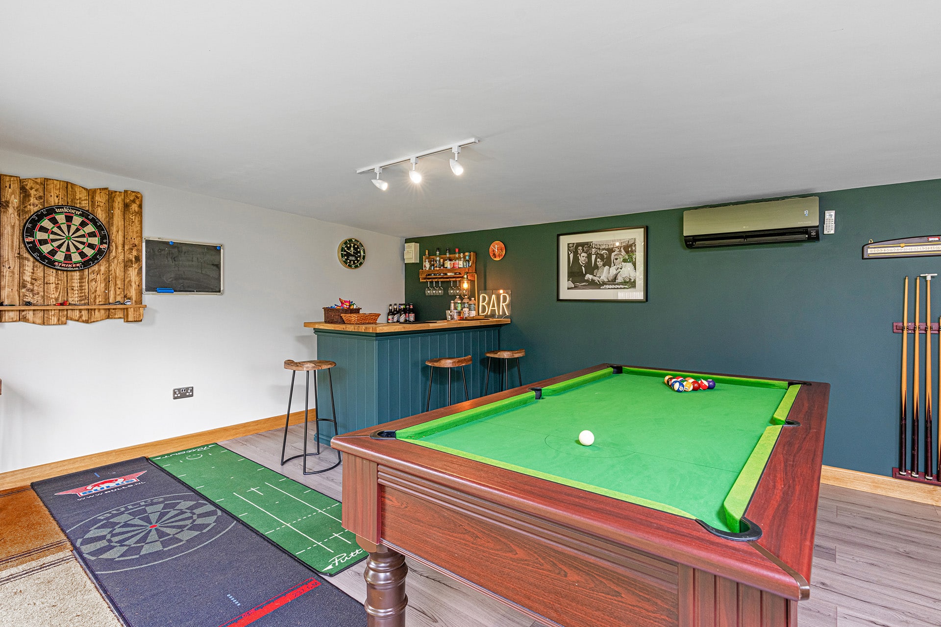 interior of a garden games room with pool table and bar with dart board