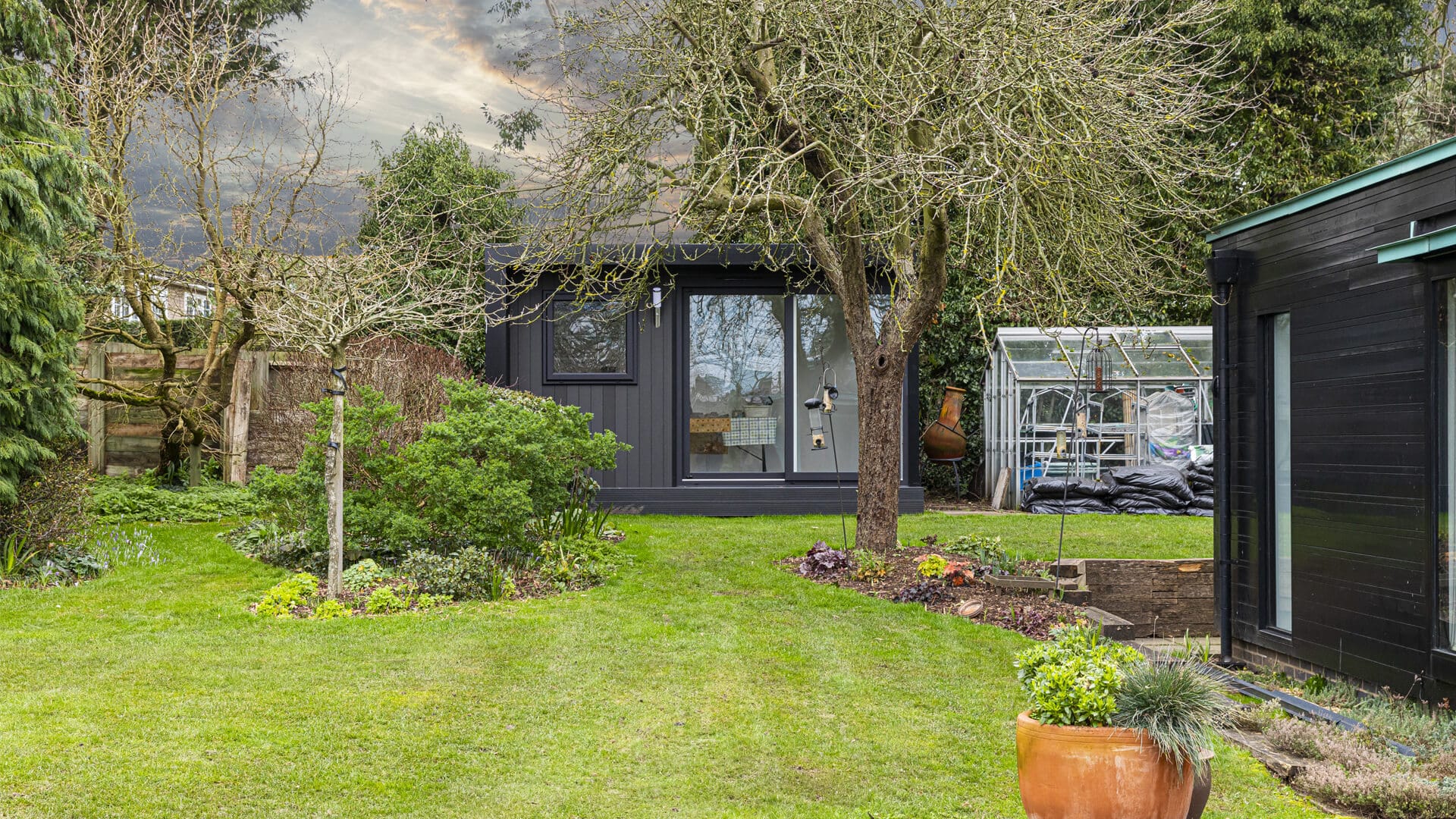 Luxury garden office with a graphite-effect exterior hidden behind some trees