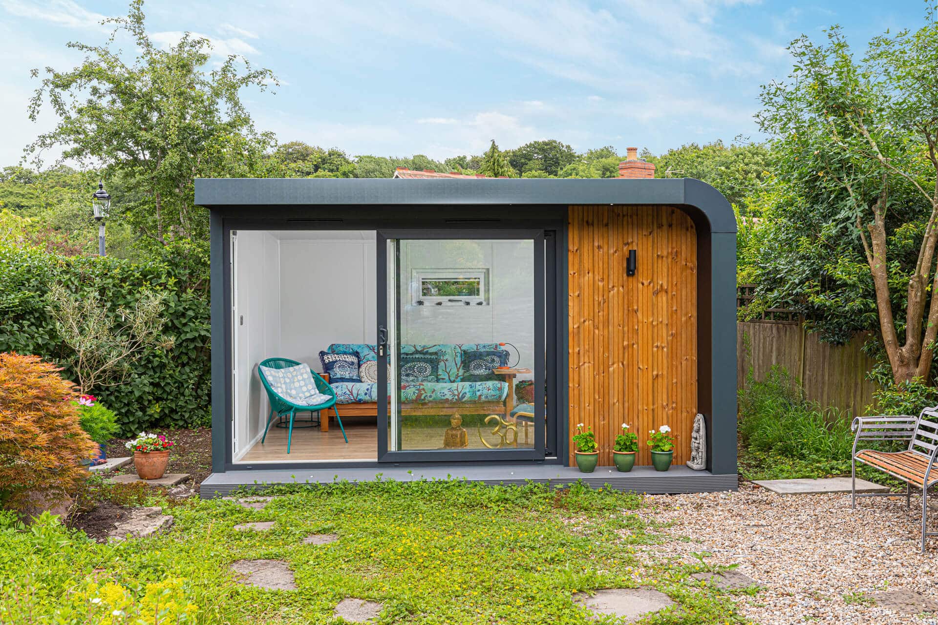 Curved graphite exterior of garden room with sliding doors open leading to comfy sofa chill out space
