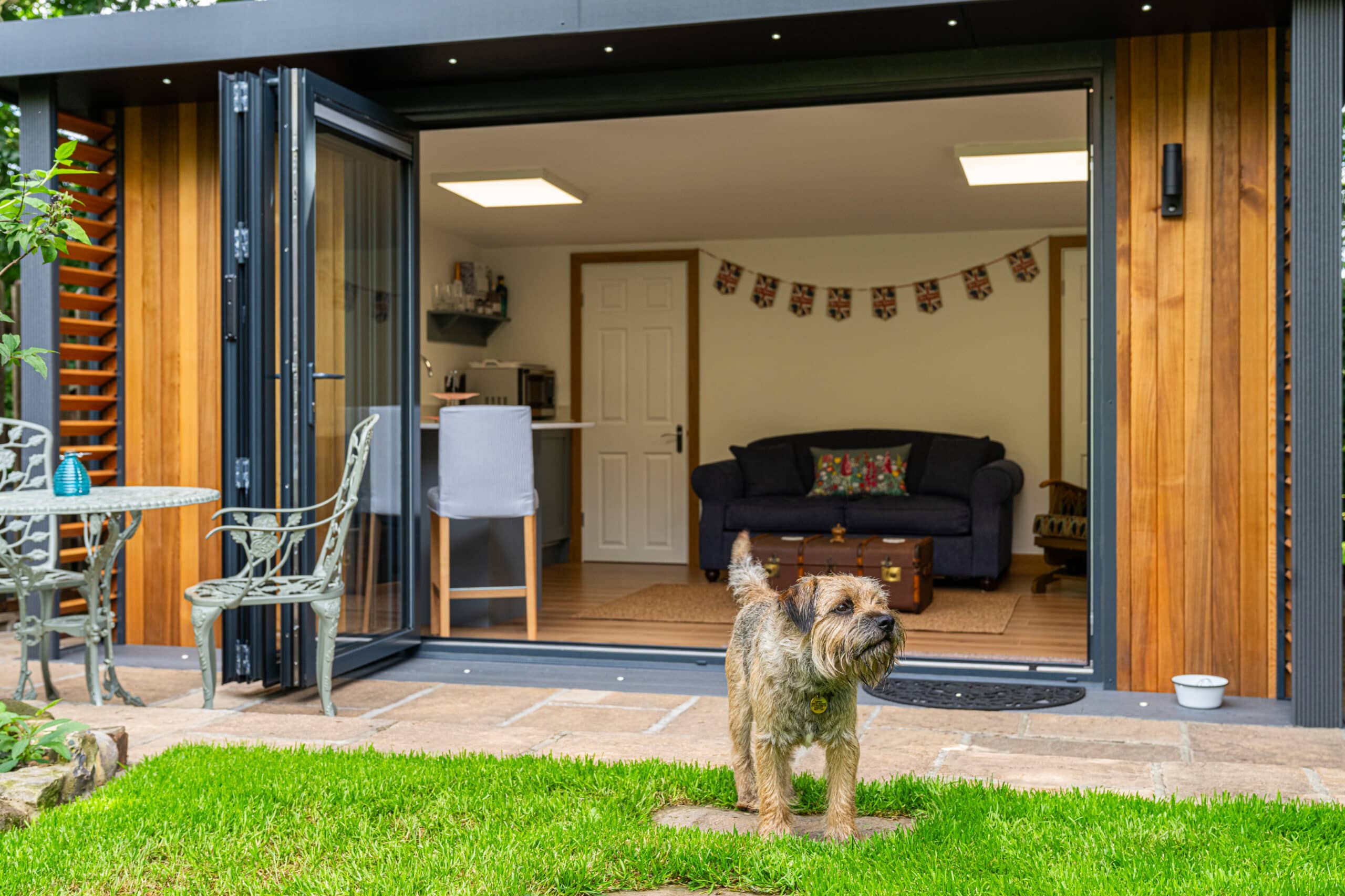 dog outside a garden room with bi-fold doors in a flourishing garden