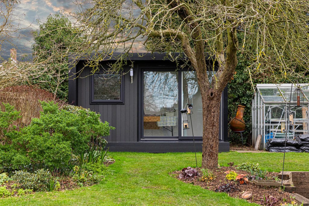 Garden room clad in black composite with sliding door to enter home art studio
