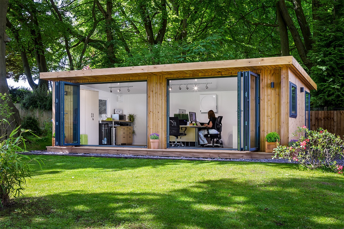 Woman working in a tranquil garden office suite surrounded by oak trees
