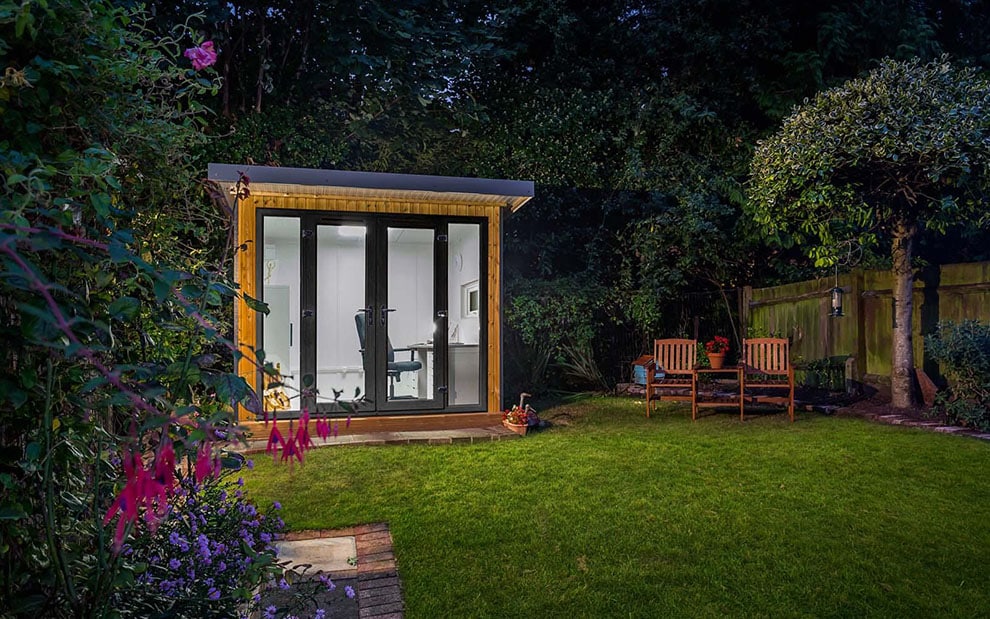 Green Retreats garden office with the lights on at night