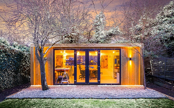 insulated garden room workshop at night in snow
