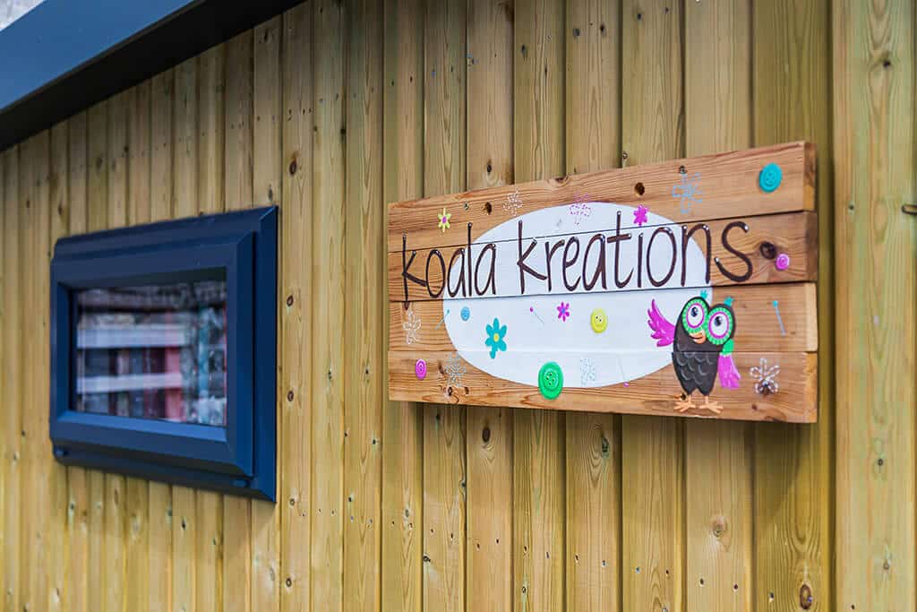 Wooden Koala Kreations shop sign nailed onto retail space garden room