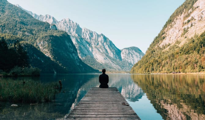 Mountain range with lake and man sitting meditating
