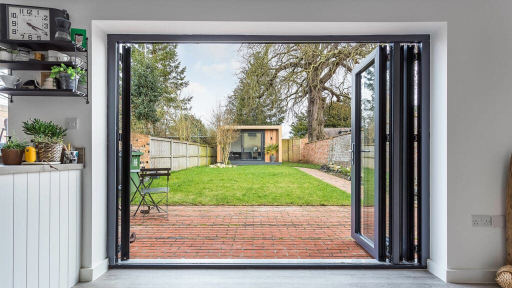 Looking through bi-folds in a kitchen to a garden room