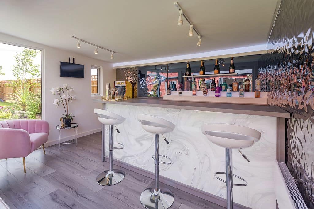 light pink garden bar with bar stools and drinks on the shelves behind the bar