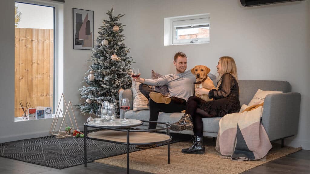 Interior of Annex at Christmas with man and woman on sofa with a Labrador
